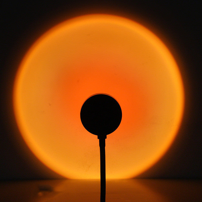 Melted Sun sunset projector, silhouette of a round object against a glowing orange circle on a dark background