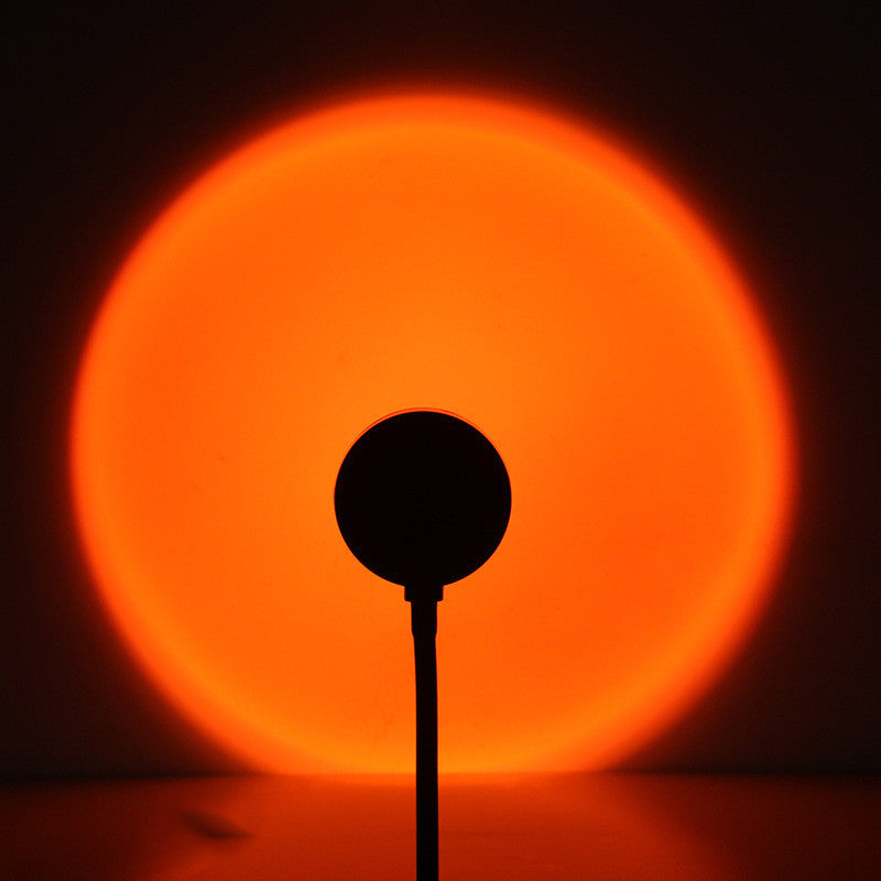 Melted Sun sunset projector, glowing circular light with a dark silhouette in the center against a black background