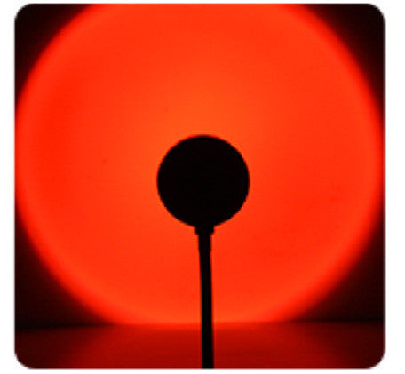 Melted Sun sunset projector, glowing circular light with a dark silhouette in the center against a black background